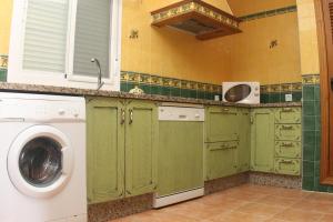 cocina con armarios verdes y lavadora en Chalet Arroyo Majadales 108, en Conil de la Frontera