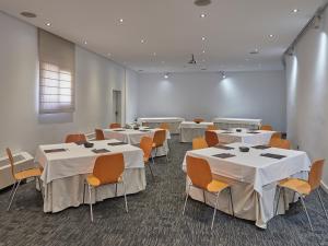 uma sala com mesas e cadeiras com toalhas de mesa brancas em BQ Augusta Hotel em Palma de Maiorca