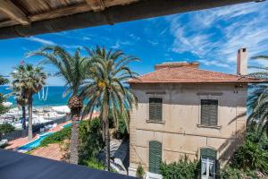 an old building with palm trees and the ocean at B&B Villa Liberty sul mare in Palermo