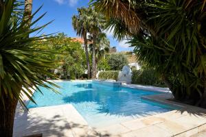 a swimming pool in a yard with palm trees at Pateo dos Solares Charm Hotel in Estremoz