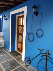 un mur bleu avec un vélo devant une porte dans l'établissement The White Balcao, à Panaji