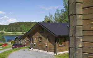 una cabaña de madera con un coche estacionado al lado de un edificio en Koivula Cottages, en Jämsä