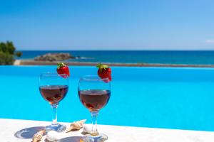 zwei Gläser Wein und Erdbeeren auf einem Tisch am Pool in der Unterkunft Mary Beach in Rodakino