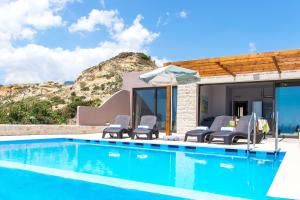 einem Pool mit Stühlen und einem Sonnenschirm neben einem Haus in der Unterkunft Mary Beach in Rodakino
