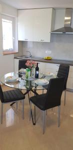 a kitchen with a glass table and black chairs at APARTMAN ANA in Mošćenička Draga