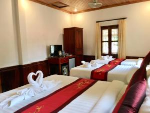 a hotel room with three beds with towels on them at Villay Vanh Place House in Luang Prabang
