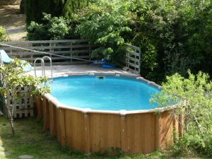 a large swimming pool in a yard with a wooden fence at Chambres d'hôtes Les Gragniotes in Tournissan