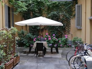 ミラノにあるOlona Place 3の白傘と花のテーブル