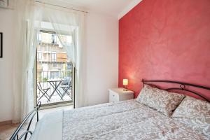 ein Schlafzimmer mit einer roten Wand, einem Bett und einem Fenster in der Unterkunft Central Balcony Apartment in Catania
