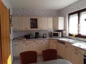 a kitchen with white cabinets and red chairs at Ferienhaus Pieper in Thale