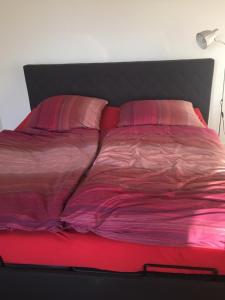 Cama roja con sábanas y almohadas rojas en Appartement Elzerland, en Mayen