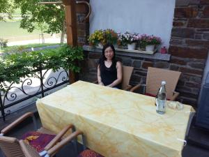 een vrouw aan een tafel op een balkon bij Gästehaus zum Moseltal in Ellenz-Poltersdorf