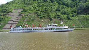 a large boat on the water near a mountain at Gästehaus zum Moseltal in Ellenz-Poltersdorf