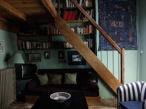 a living room with a couch and a staircase with books at Maison d'Almes in Adissan