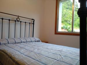 1 cama en un dormitorio con ventana y colcha en Casa en Ribeira Sacra, en Viñoás
