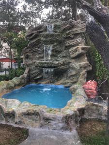 ein Wasserfall in einem Felsenbrunnen in einem Garten in der Unterkunft Hotel Evrazia in Ureki