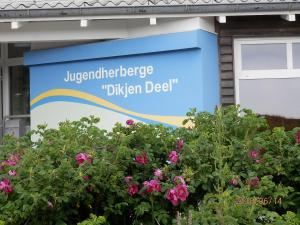 a sign in front of a building with flowers at Jugendherberge Westerland in Westerland (Sylt)