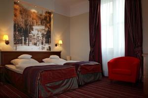 Pokój hotelowy z 2 łóżkami i czerwonym krzesłem w obiekcie Branicki Boutique Rooms w mieście Białystok