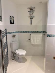 a white bathroom with a toilet and a cross on the wall at Postman's Knock, Lynmouth, first floor apartment with private parking in Lynmouth