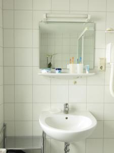 a white bathroom with a sink and a mirror at Uns Gartenhus in Klein Zicker