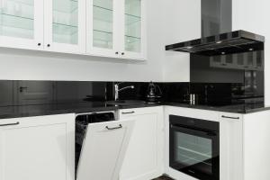 een keuken met witte kasten en een zwarte oven bij Apartamenty Morska Fala-Gardenia in Dziwnów