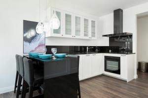 a kitchen with white cabinets and blue bowls on a counter at Apartamenty Morska Fala-Gardenia in Dziwnów