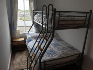 2 Etagenbetten in einem Zimmer mit Fenster in der Unterkunft Coastal View in Bushmills