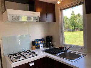 a kitchen with a stove and a sink and a window at LE MEDOC AUX 4 VENTS in Jau-Dignac-et-Loirac