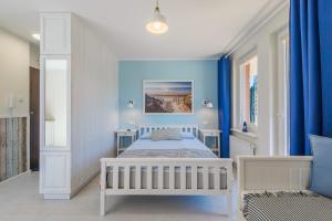 a bedroom with a white bed and blue walls at Błękitne Zacisze in Sztutowo