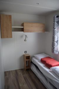 a small bedroom with a bed and a small table at Camping des Joyeux Campeurs in Pont-sur-Seine