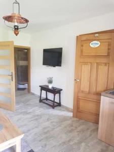 Zimmer mit einer Tür, einem Tisch und einem TV in der Unterkunft Chata Pod Strzechą in Lipusz