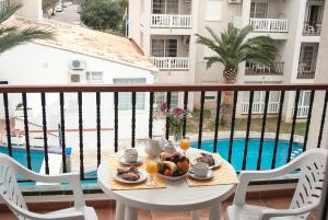 una mesa con comida y bebida en un balcón con piscina en Ona Ogisaka Garden, en Denia