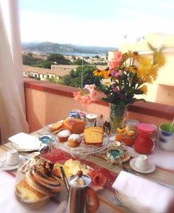 una mesa con un plato de comida y un jarrón de flores en The Roses Garden en La Maddalena