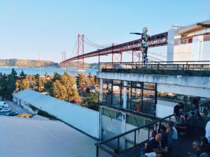 a group of people sitting on top of a building with a bridge at TryLisbon Calvário in Lisbon