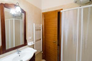 Un baño con lavabo, espejo y ducha. en DIMORA ALFAS, en Borgagne