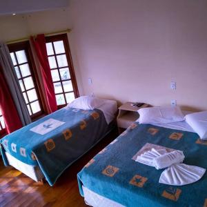 1 dormitorio con 2 camas y 2 ventanas en Hotel Solare, en Santana do Livramento