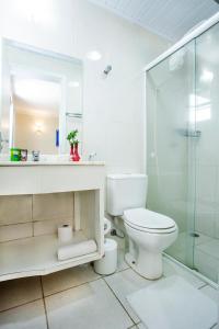 a bathroom with a toilet and a glass shower at Pousada Azul da Cor do Mar in Maresias