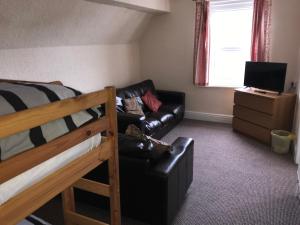 a bedroom with a bunk bed and a black leather couch at Beach View Holiday Flats in Blackpool