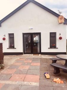 un edificio blanco con una mesa y un banco en Teach Beag Cois Tra, en Miltown Malbay