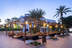 patio z kanapami, stołami i palmami w obiekcie FERGUS Style Bahamas w mieście Playa d'en Bossa