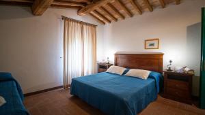 a bedroom with a blue bed with a wooden headboard at Poggio Al Palio in San Lorenzo a Merse