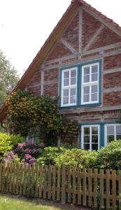 a wooden fence in front of a house with flowers at elbe511ferienzuhause in Dömitz