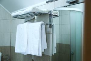 La salle de bains est pourvue de serviettes blanches suspendues à un porte-serviettes. dans l'établissement Pensiunea Alexia, à Iaşi