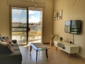 ein Wohnzimmer mit einem Sofa, einem TV und einem Tisch in der Unterkunft Our Place At The Desert in Midreshet Ben Gurion