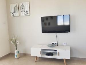 un armario blanco con TV en una pared blanca en Our Place At The Desert, en Midreshet Ben Gurion