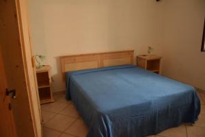 una camera con un letto blu e due tavoli di Casa Gardenia a San Pietro in Bevagna