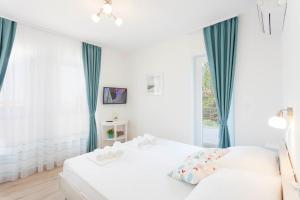 a white bedroom with two beds and a window at Blue House in Makarska