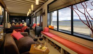 a room with couches and a window with a view of the ocean at NOI Indigo Patagonia in Puerto Natales