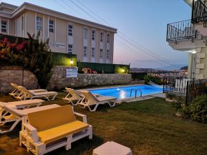 um quintal com piscina e cadeiras e um edifício em Kandıra Butik Hotel em Cesme