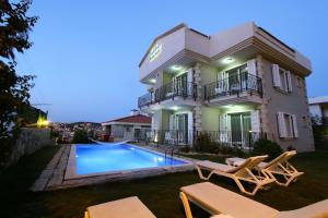 a villa with a swimming pool in front of a house at Kandıra Butik Hotel in Çeşme